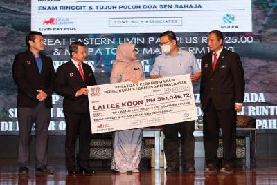 Fadhlina (tengah) menyerahkan replika cek kepada waris mendiang, Tong Chee Kong iaitu suami mendiang Lai Lee Koon dari SJKC Mun Choong yang merupakan ahli NUTP. -Foto Bernama