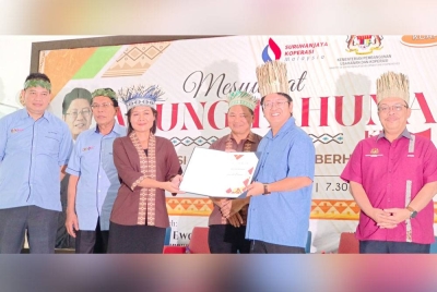 Ewon (dua dari kanan) menyampaikan sijil kepada ahli Koperasi Orang Asli Perak Berhad pada program Sesi Sembang Santai Bersama Masyarakat Orang Asli Perak di Simpang Pulai pada Sabtu.