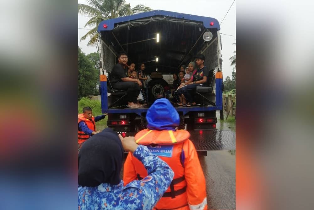 Anggota Angkatan Pertahanan Awam.(APM) membantu memindahkan mangsa banjir dari Kampung Seri Damai ke PPS di dewan orang ramai kampung itu pada Isnin.