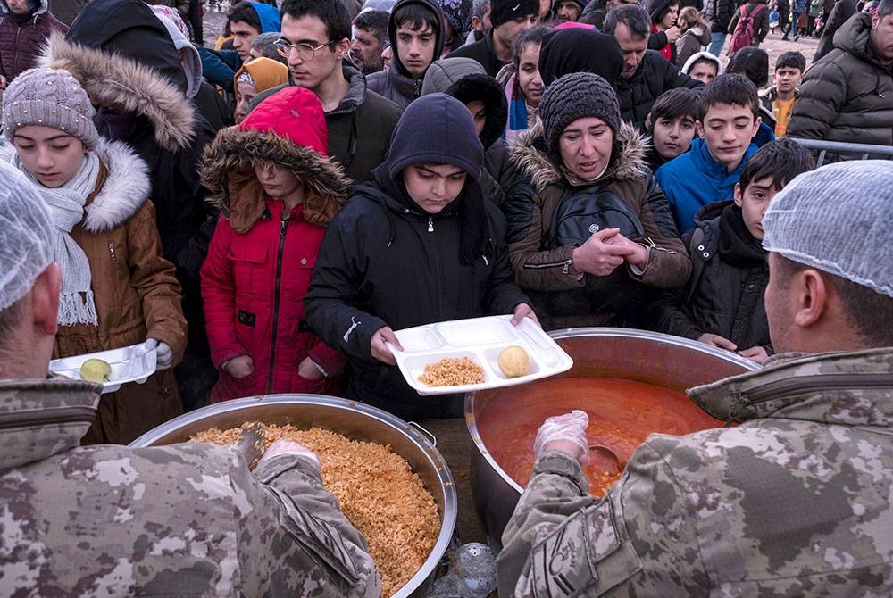 Orang ramai menerima makanan percuma yang diagihkan selepas gempa bumi di Diyarbakir, tenggara Turki pada Isnin. - Foto EPA