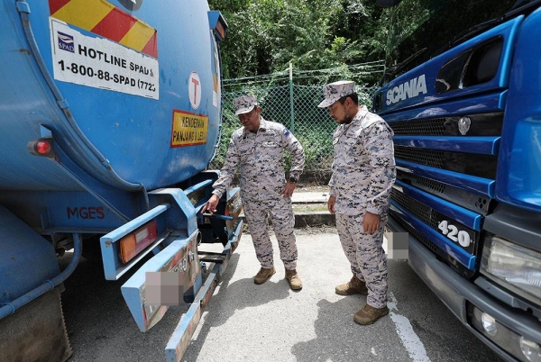 Nurul Hizam (kiri) dan Pemangku Pengarah Zon Maritim Tanjung Sedili, Komander Maritim Mohd Najib Sam menunjukkan dua buah lori tangki yang turut dirampas bersama sebuah kapal tangki kerana disyaki untuk aktiviti pemindahan minyak diesel secara haram ketika sidang media Pos Maritim Pengerang, Tanjung Pengelih pada Selasa. - Foto Bernama