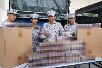 Mohd Khairulanuar (dua dari kanan) menunjukkan antara rokok seludup yang dirampas dalam operasi khas yang dijalankan di muara Kuala Besut, di Besut pada awal pagi Selasa.
