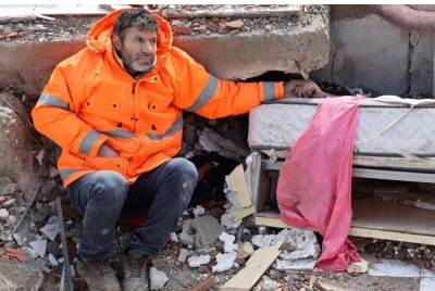 Mesut merenung ke arah kejauhan dengan pandangan kosong sambil memegang tangan mayat anaknya yang dihimpit antara dua kepingan konkrit. - Agensi