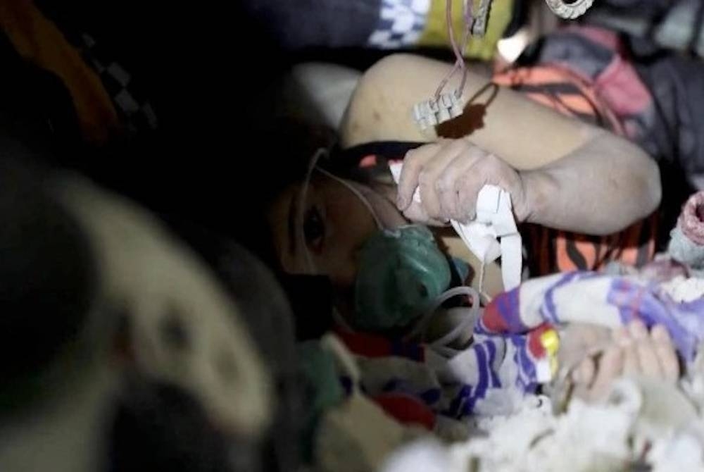 Kanak-kanak itu sedang menerima oksigen dengan berlindungkan batu daripada runtuhan bangunan.