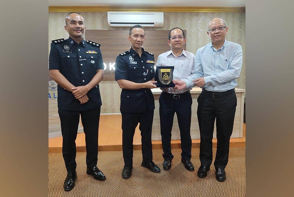 Ahmad Ridhwan (dua dari kiri) menyerahkan cenderamata kepada Boon Soon ketika majlis penyerahan bot penyelamat di IPD Kuala Langat.