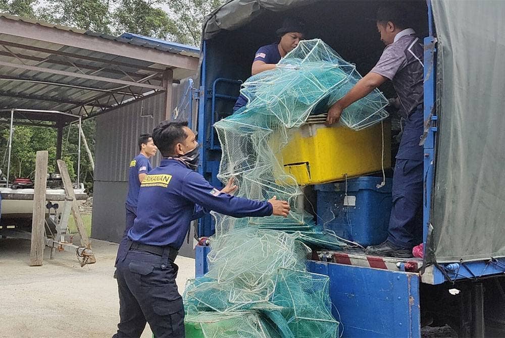 Anggota penguat kuasa Jabatan Perikanan Selangor membawa turun bubu naga yang dirampas di Pusat Tahanan Vesel Kuala Selangor di sini pada Jumaat.