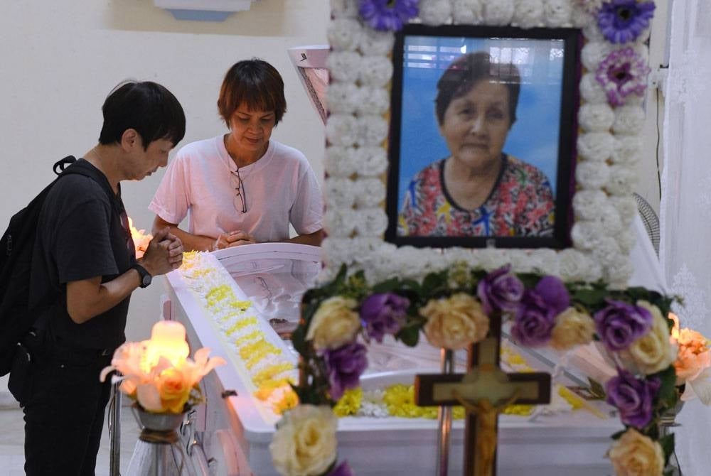 Nyok Sin (dua dari kiri) anak kepada mendiang Ah Mooi bersama adik kepada mendiang Nancy Wong, 60, memberi penghormatan terakhir terhadap mendiang di kediamannya Machang Bubok pada Jumaat. - Foto Bernama