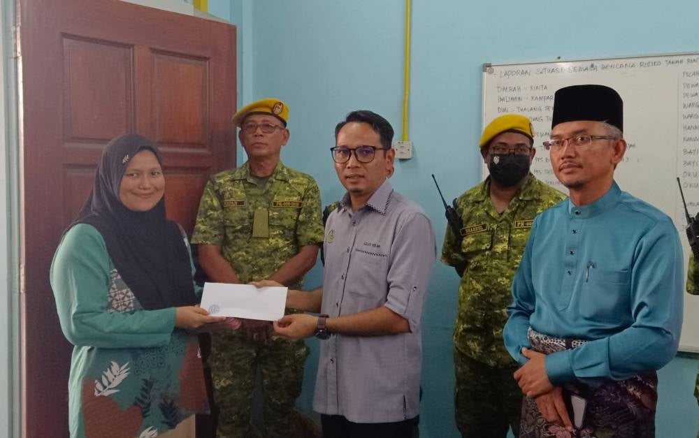 Mohd Azlan (tiga dari kanan) menyampaikan sumbangan kepada penduduk yang terjejas akibat cerun runtuh di PPS Dewan Serba guna Tanjung Tualang. 