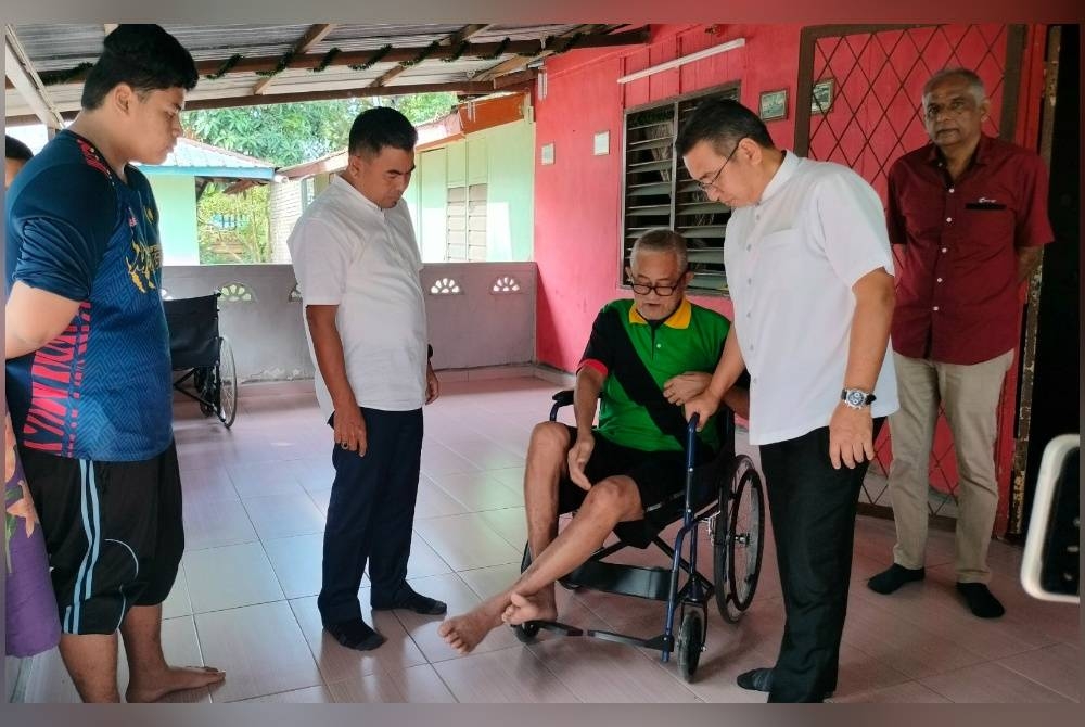 Adly (empat,kiri) ketika menyampaikan kerusi roda kepada Abdul Latip di Kampung Gangsa pada Sabtu.