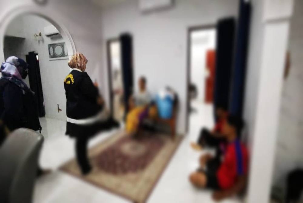 Penguat kuasa JAIM (kiri) ketika menahan mereka di sebuah rumah di Lipat Kajang, Jasin pada malam Jumaat.