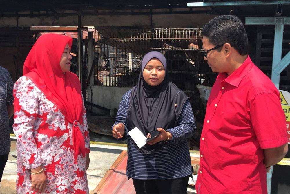 Timbalan Ketua UMNO Bahagian Pasir Salak, Khairul Azwan Harun (kanan) dan Ketua Wanita UMNO Perak, Datuk Dr Wan Norashikin Wan Noordin (kiri) menyampaikan sumbangan kepada salah seorang mangsa yang terlibat dalam kebakaran enam kedai di Jalan Ulu Dedap, Kampong Gajah.
