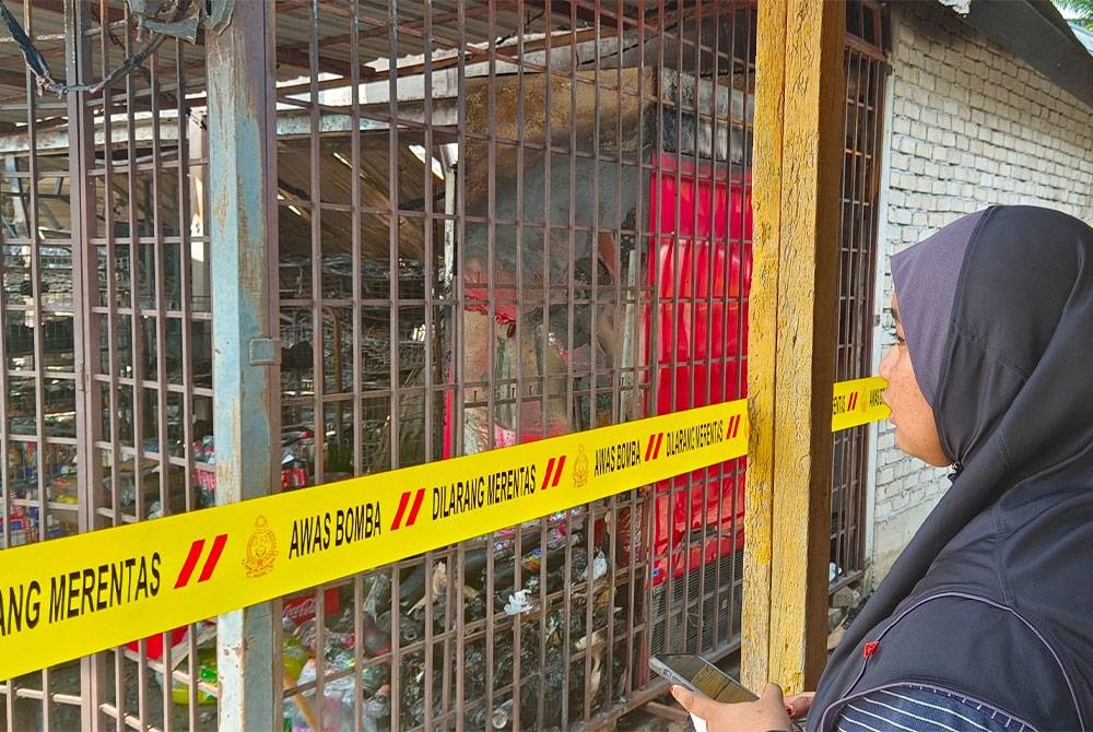 Salah seorang mangsa sebak melihat kedai runcit milik keluarganya musnah dalam kebakaran di Kampong Gajah pada Jumaat.