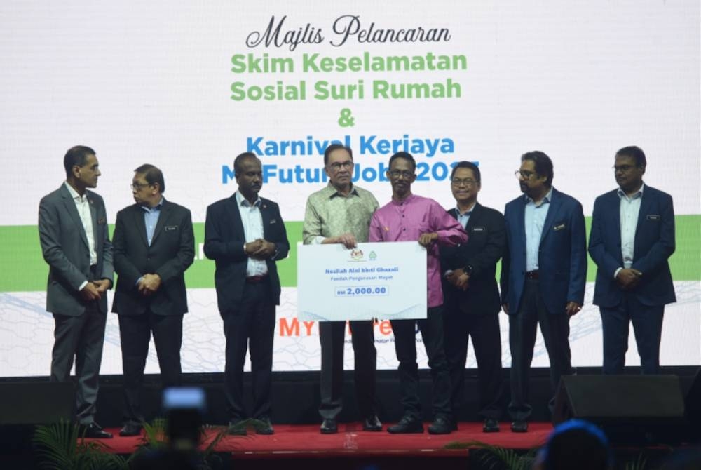 Sivakumar (tiga dari kiri) dan Anwar (empat dari kiri) ketika menyampaikan cek kepada waris suri rumah berinsurans yang menerima Faedah Pengurusan Mayat dan bayaran Pencen Penakat. - Foto RAFEQ REDZUAN