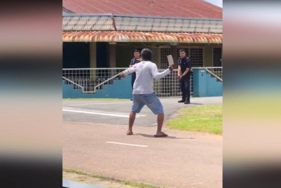 Tangkap layar video tular memaparkan dua anggota polis memujuk seorang lelaki yang memegang pisau pemotong daging di Paloh.