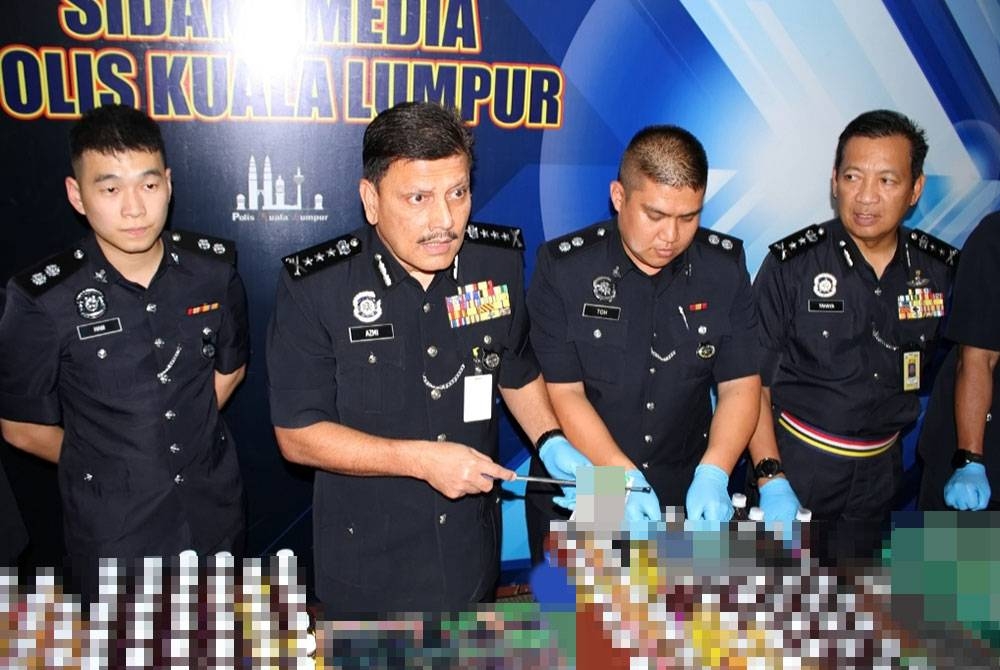 Azmi (dua kiri) menunjukkan minuman disyaki berisi dadah yang dirampas dalam serbuan polis, baru-baru ini. - Foto Polis KL