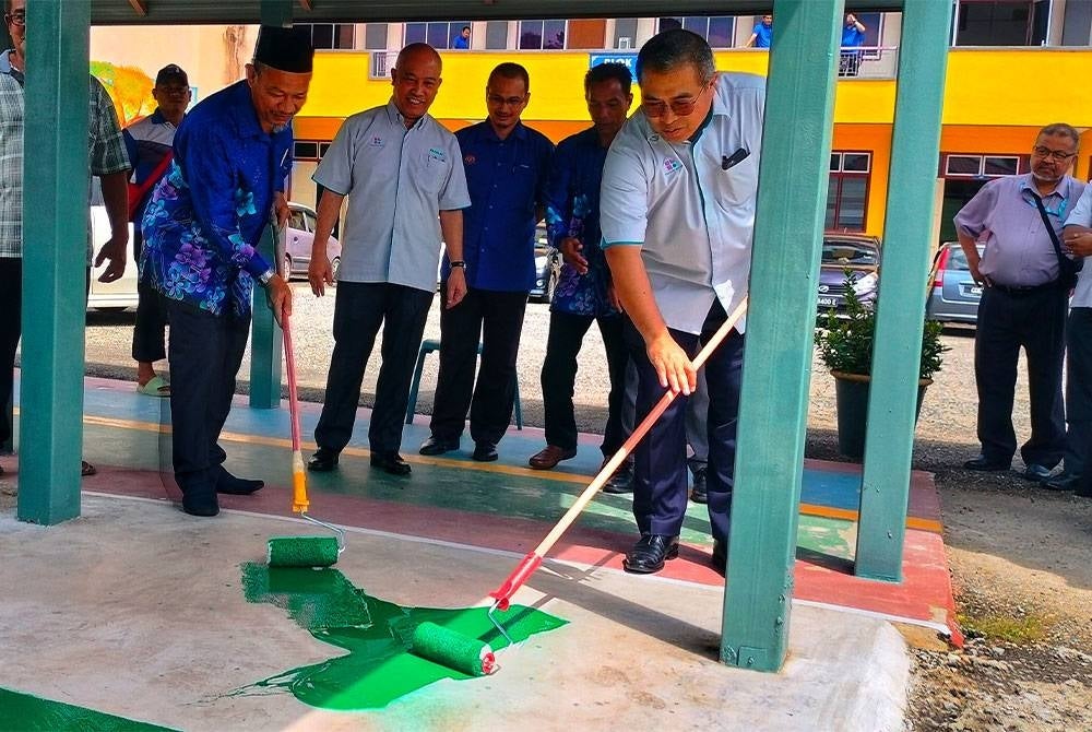 Abdul Hadi (kanan) bersama Wan Mohd Iskandal mengecat laluan pejalan kaki yang menjadi salah satu program CSR PAAB di sekolah berkenaan.