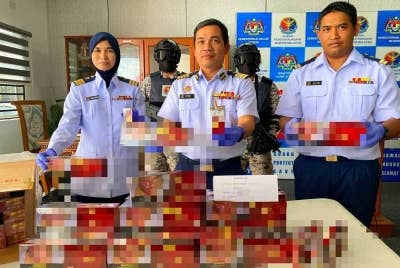 Syed Nor Adli (tengah) bersama pegawainya menunjukkan sebahagian daripada rokok putih yang berjaya dirampas di Pengkalan Kubor, Tumpat.