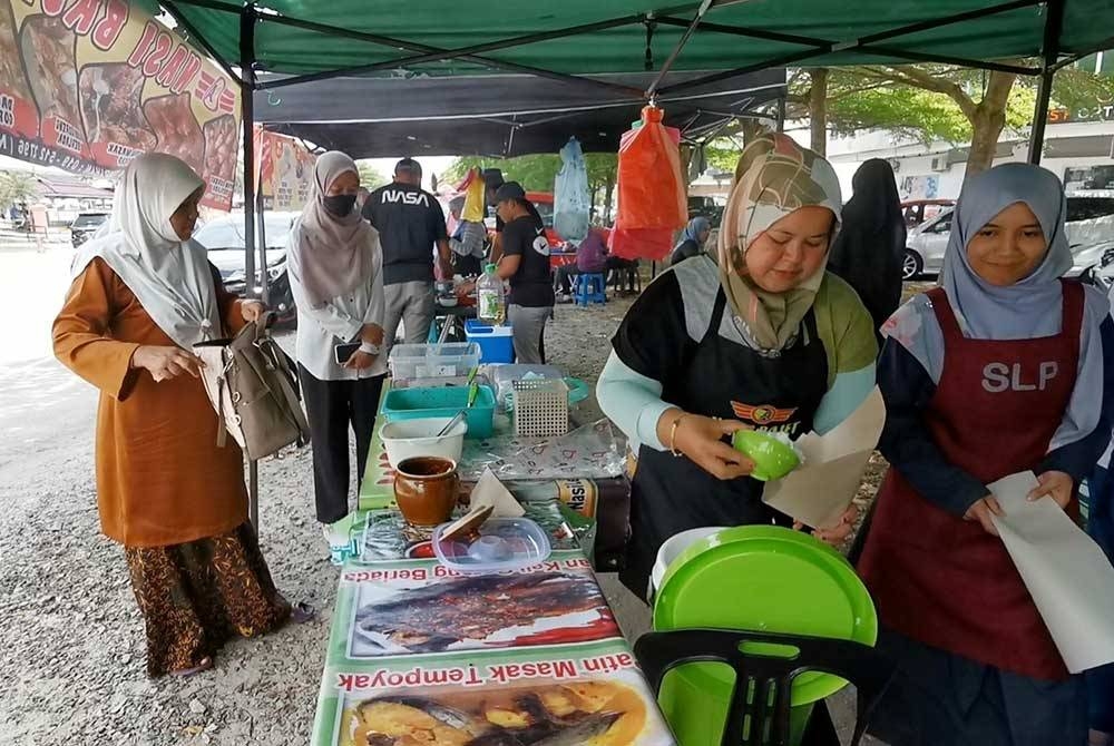 Hasriah (kanan) melayani pelanggan yang berkunjung ke gerainya yang beroperasi berhampiran pasar raya Mydin di Gong Badak, Kuala Nerus.