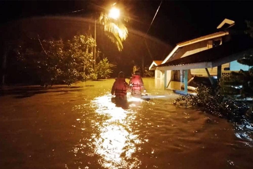 Anggota bomba membuat pemantauan keadaan banjir yang berlaku di Kampung Pasir, Temoh. - Foto Bomba Perak