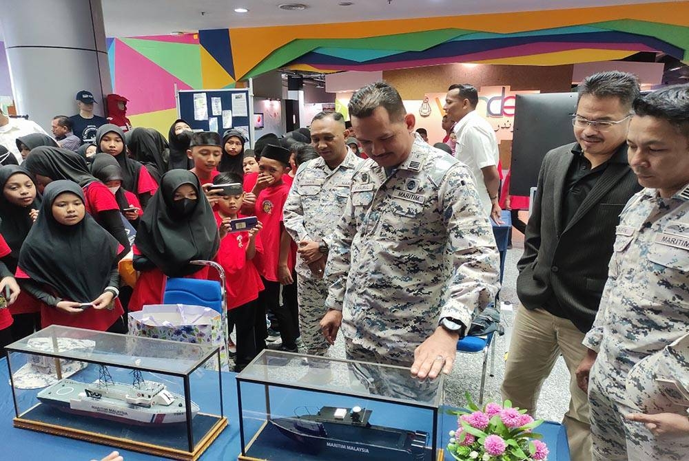 Khairulanuar (tiga dari kanan) memberi penerangan kepada pelajar sekolah yang mengunjungi pameran sempena Sambutan Hari Ulang Tahun Maritim Malaysia ke-18 di Pusat Sains dan Kreativiti Terengganu (PSKT), di sini pada Rabu.