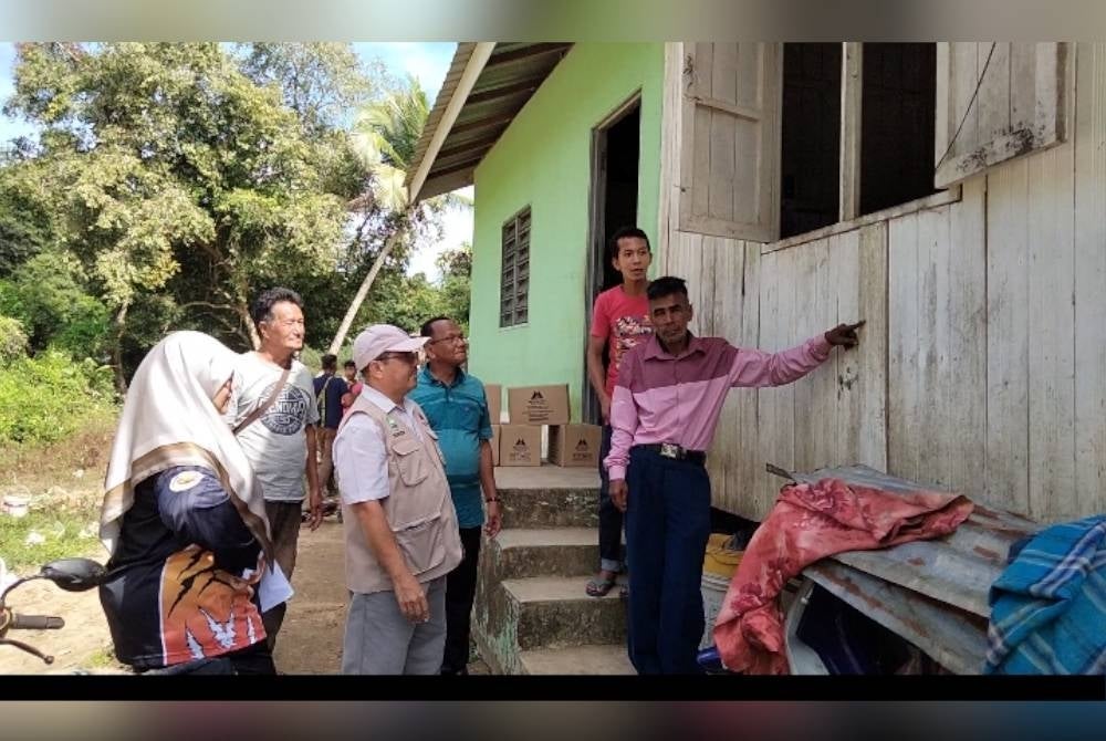 Mohd Jusoh (kanan) menunjukkan paras air ketika rumah mereka dilanda banjir akhir tahun lalu.