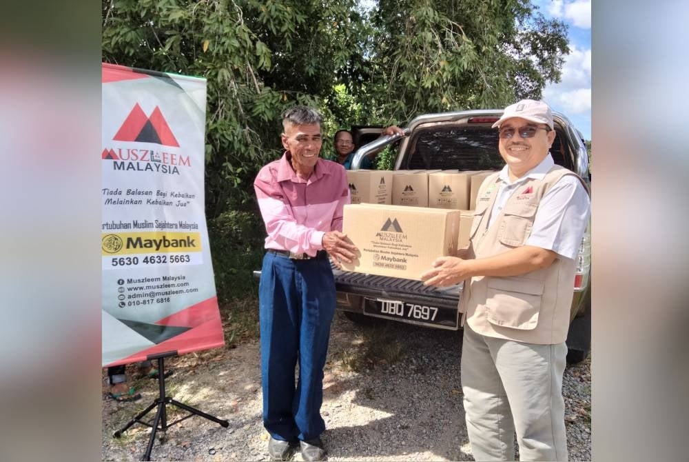 Mohd Jusoh (kiri) menerima sumbangan daripada Rostam