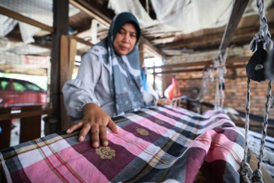 Gayah memeriksa tenunan songket yang dihasilkannya dengan hanya menggunakan jari. - Foto Bernama