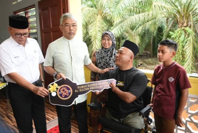Al-Sultan Abdullah diiringi Wan Rosdy menyerahkan kunci rumah kurniaan Yasa kepada Mohd Khairi dalam majlis penyerahan di Kampung Tanjung Pulai,Pekan pada Rabu.