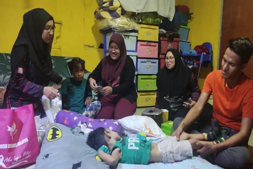 Zuraini (kiri) mewakili CSM hadir menyampaikan sumbangan kepada Muhammad Aqil Sudais di Kampung Pida 8, Tandop, Ayer Hitam pada Rabu.