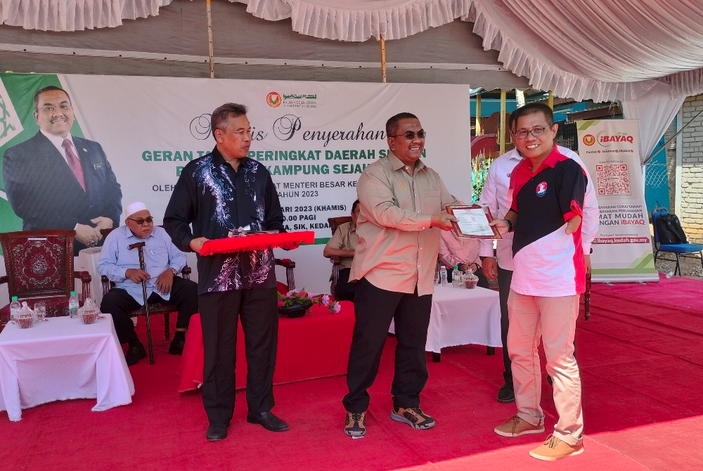 Muhammad Sanusi menyerahkan geran tanah kepada penduduk Kampung Sejahtera, Sik pada Khamis.