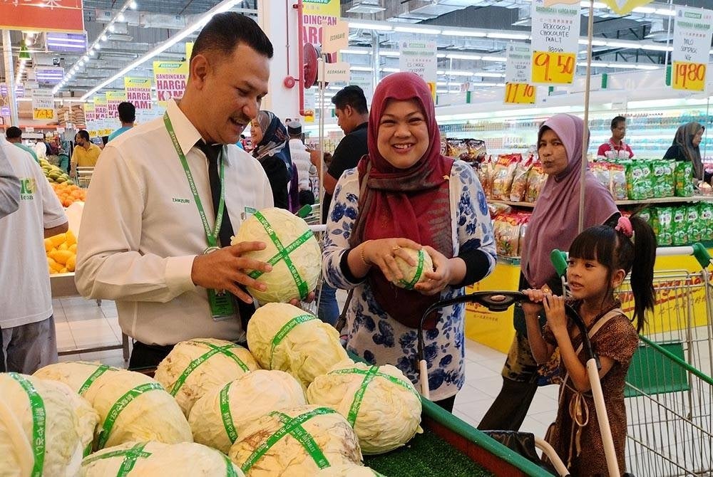 Zamzuri (kiri) melayan pelanggan yang hadir sempena pembukaan cawangan baharu EconSave di Baling.