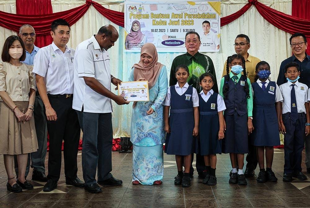  Menteri Pendidikan Fadhlina Sidek (lima, kiri) menyampaikan bantuan persekolahan kepada Guru Besar Sekolah Kebangsaan Jenis Tamil (SJKT) Nibong Tebal Selva Kumaran (empat, kiri) mewakili murid sekolah kurang berkemampuan pada Program Penyerahan Bantuan Persekolahan hari ini. - Foto Bernama.
