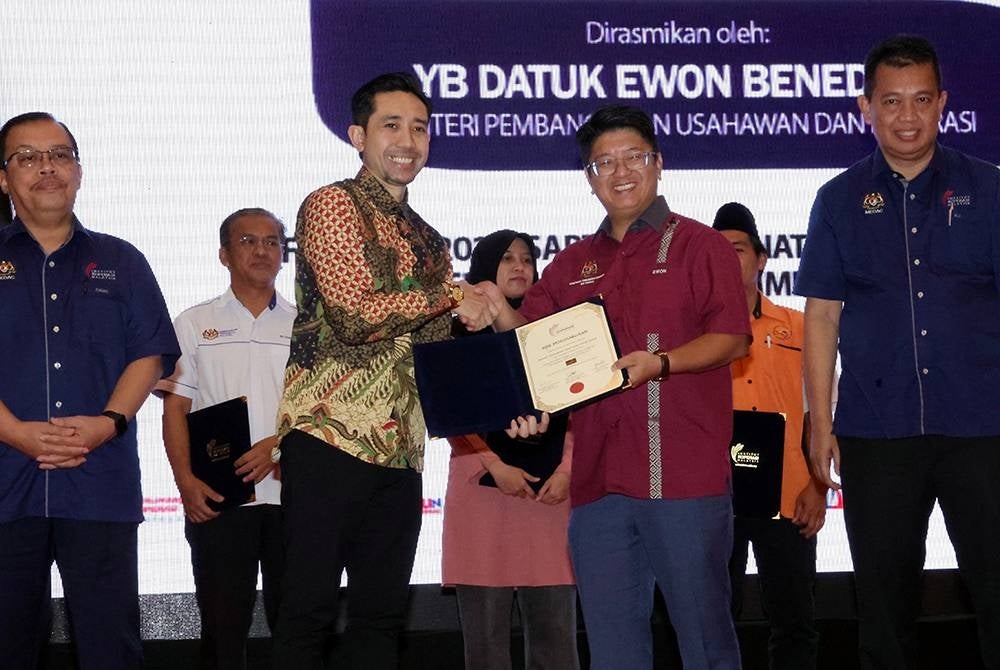 Ewon (dua dari kanan) menyampaikan bantuan kepada pengusaha persatuan koperasi sempena Program Memasyarakatkan Koperasi di Pusat Antarabangsa Teknologi dan Komersial (ITCC) Penampang pada Sabtu. - Foto Bernama