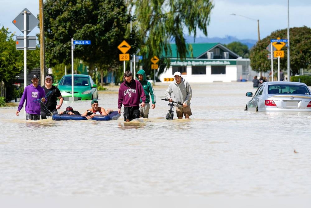 Orang ramai mengharungi air banjir di bandar Napier, yang terletak di pantai timur Pulau Utara, New Zealand pada Rabu. - Foto AFP