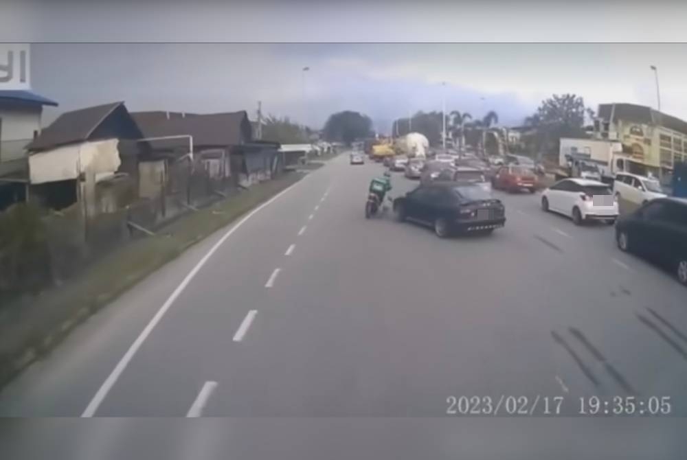 Tangkap layar video yang tular menunjukkan seorang penghantar makanan terjatuh selepas dilanggar kereta yang menukar lorong secara mengejut di Jalan Kuala Kangsar pada Jumaat.