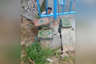 Seorang lelaki berada di dalam longkang sedang mengutip al-Quran.