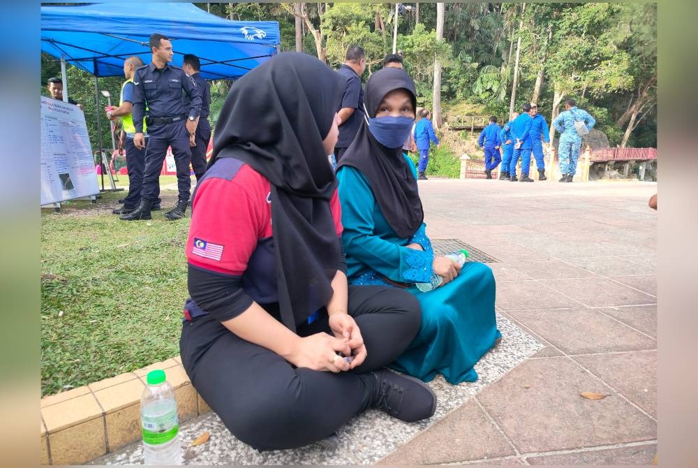 Saidatul Alia (kiri) bersama ibunya berada di lokasi bagi mengikuti perkembangan pencarian adiknya yang dikhuatiri lemas di Pantai Teluk Chempedak di sini pada Isnin.