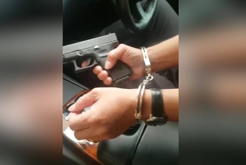 Tular video di laman sosial memaparkan seorang individu memegang pistol dalam keadaan tangan bergari pada Jumaat.