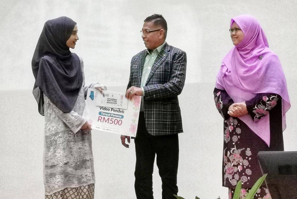 Hanafiah (tengah) menyampaikan hadiah kepada pemenang pertandingn kategori video pendek, Hanim Sophia Sohor (kiri) sempena sambutan Terengganu Hijab Day di Kompleks Pentadbiran Bandar Al Wathiqu Billah di Kuala Nerus.