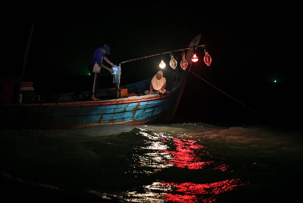 Nelayan, Mohd Sohir Man, 60, bersama isterinya, Habsah Ahmad, 52, melakukan aktiviti mencandat sotong di kawasan perairan Kuala Sala berhampiran Pulau Bunting di sini.