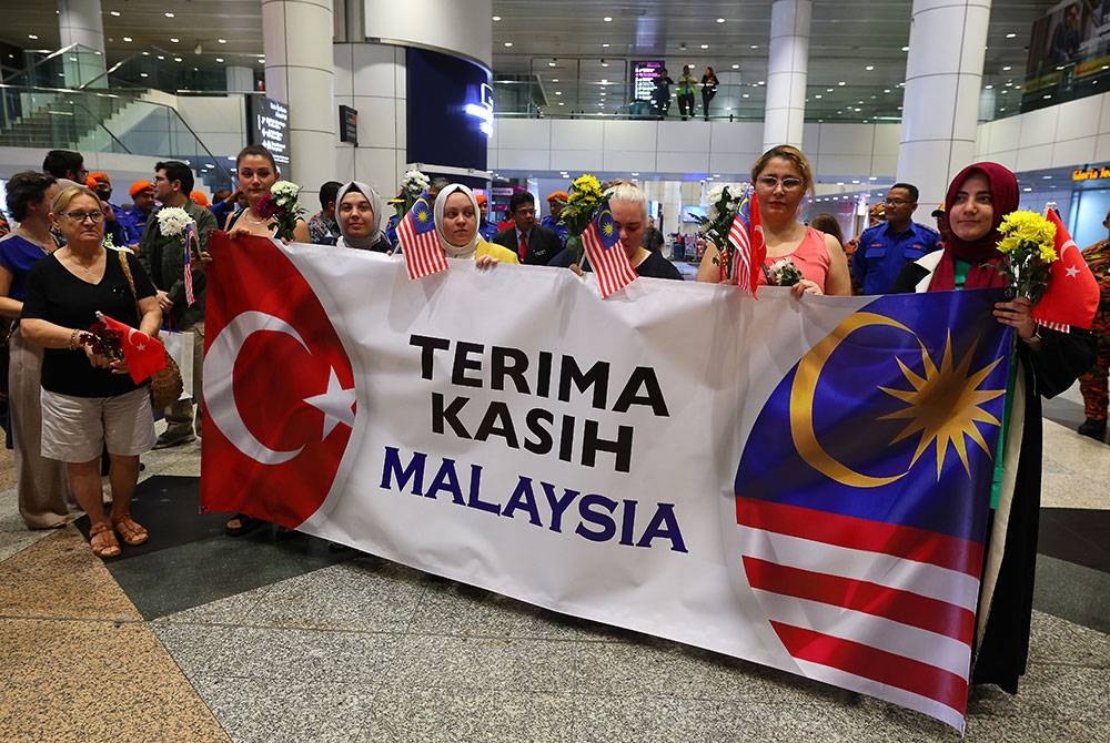 Warga Turkiye di Malaysia meluangkan masa menyambut ketibaan anggota Kumpulan Kedua (MAS-10) Pasukan Mencari dan Menyelamat Malaysia (SAR) dengan membawa banting tertera 'Terima Kasih Malaysia' di Lapangan Terbang Antarabangsa Kuala Lumpur (KLIA) hari ini.