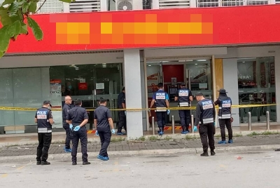 Anggota polis sedang menjalankan siasatan di lokasi rompakan sebuah bank di Setia Alam pada Khamis.