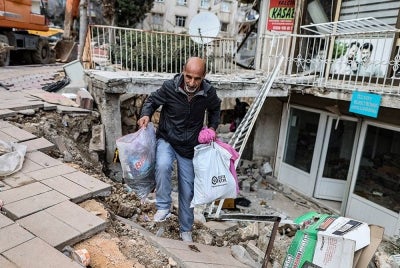 Orang ramai mengutip barang-barang mereka dari runtuhan bangunan selepas gempa bumi kuat di Hatay, Turki pada Selasa.