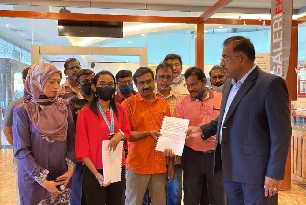 Vijaya Gomaran (tengah) menyerahkan memorandum
kepada Gunarajah (kanan) pada Jumaat.