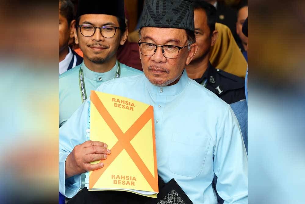 Anwar menunjukkan beg yang mempunyai dokumen Belanjawan 2023 sebelum bergerak menuju ke Bangunan Parlimen dari Kementerian Kewangan pada Jumaat. - Foto Bernama