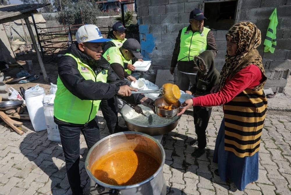 Sebahagian sukarelawan menyediakan masakan panas yang dimasak menggunakan dapur kayu untuk dihidangkan kepada kira-kira 200 mangsa gempa bumi yang terjejas di sekitar Hatay, Turkiye.