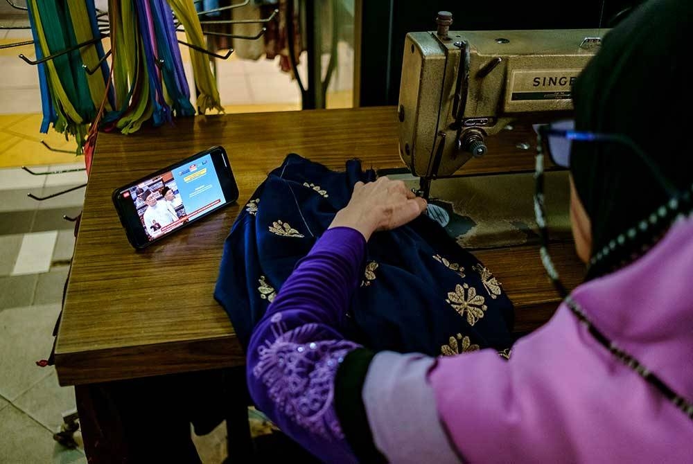 Usahanita Siti Hartini Rasudin yang mengusahakan perniagaan jahitan mendengar pengumuman Belanjawan 2023 Malaysia MADANI oleh Perdana Menteri Datuk Seri Anwar Ibrahim, ketika tinjauan hari ini.