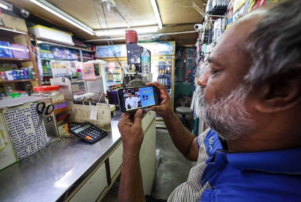 Mohd Naser Abdul Salam, 55, tidak melepaskan peluang menyaksikan siaran langsung Belanjawan 2023 Malaysia MADANI yang dibentangkan oleh Perdana Menteri yang juga Menteri Kewangan Datuk Seri Anwar Ibrahim di kedai runcitnya hari ini.