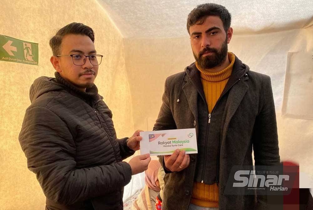 Pengurus Besar Syria Care, Muaz Abd Muein (kiri) menyampaikan bantuan kewangan Tabung #BantuanBencana Sinar Harian x Syria Care kepada keluarga Amjad Al-Ahmad, pelarian Syria yang menetap di Turkiye.