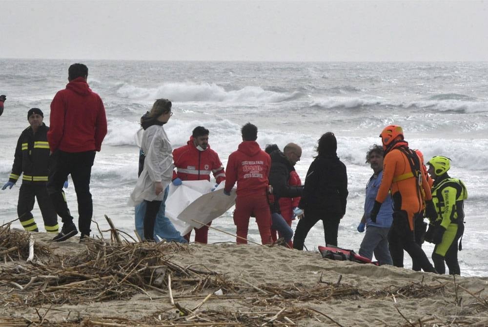 Anggota bomba dan anggota Palang Merah berkumpul di tempat kejadian di mana mayat pendatang dihanyutkan ke darat berikutan kapal karam, di pantai berhampiran Cutro, wilayah Crotone, selatan Itali. - Foto EPA